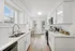Bright and modern kitchen featuring sleek white cabinetry, stainless steel appliances, and elegant wood flooring, with a cozy dining nook.