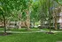 Charming apartment complex surrounded by lush greenery and scenic pathways, offering serene outdoor spaces with mature trees and inviting picnic areas.
