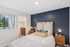 Chic bedroom with elegant decor, large window, and walk-in closet, featuring a cozy bed with stylish pillows and vibrant accent wall.