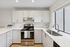 Modern kitchen with sleek white cabinetry, stainless steel appliances, and elegant countertops, offering a bright and inviting space for culinary creativity.