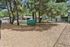 Charming outdoor space with lush trees, a green play tunnel, and cozy picnic tables, perfect for relaxation and family enjoyment.