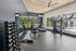 Modern apartment fitness center with high ceilings, large windows, and a fully equipped gym area.