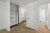 Elegant bedroom with mirrored closet doors, plush carpet, and stylish wooden flooring leading to a modern bathroom.