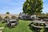 Charming outdoor space with picnic tables on lush green lawn under a shady tree, ideal for gatherings and relaxation.