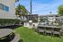 Inviting outdoor courtyard featuring a modern barbecue area, green lawn, and seating adjacent to a refreshing swimming pool.
