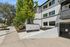 Charming apartment complex entrance with modern white stucco buildings, lush greenery, and vibrant landscaping at Arrive on the Hill.