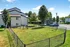Charming apartment complex exterior featuring lush green lawns, mature trees, and a peaceful setting with ample parking.
