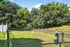 Inviting fenced pet-friendly area with lush greenery and vibrant trees under a clear blue sky, perfect for outdoor enjoyment.