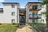 Charming modern apartment building with stylish balconies and elegant exterior, nestled in a lush green environment.