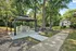 Charming outdoor area with a modern gazebo and barbecue grill nestled among lush trees for a serene experience.