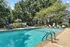 Inviting outdoor swimming pool area with comfortable loungers and elegant poolside seating, surrounded by lush greenery.