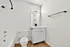 Bright, modern bathroom featuring sleek white cabinetry, stylish fixtures, and elegant wooden flooring.