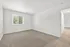 Bright and airy bedroom with plush carpet, large window offering a scenic view, and a clean white aesthetic.