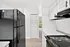 Bright and modern kitchen with sleek black appliances, white cabinetry, and a cozy view leading to the outside balcony.