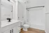 Elegant bathroom featuring a sleek white vanity, modern fixtures, and a tiled shower-bath combination, perfect for relaxation.
