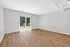 Bright and airy room with elegant wood flooring, featuring large sliding glass doors opening to a lush green view.