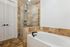 Elegant bathroom featuring a luxurious soaking tub and a modern glass-enclosed shower with stylish beige tile accents.