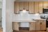 Modern kitchen with elegant wooden cabinets, sleek white countertops, and a stainless steel stove, offering a stylish and functional cooking area.