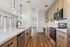 Modern kitchen with sleek stainless steel appliances, elegant pendant lighting, and chic wooden cabinetry in a sunlit open layout.