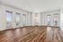 Bright and spacious living room with elegant wood flooring, large windows, and French doors leading to a scenic balcony view.