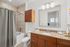 Elegant bathroom with a granite countertop, wood cabinetry, and a tiled shower area for a luxurious living experience.