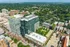 Stunning aerial view of modern apartment complex in a vibrant neighborhood, surrounded by lush greenery and bustling city life.