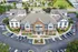 Aerial view of a modern apartment complex with ample parking, lush green landscaping, and convenient access to nearby amenities.