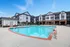 Stunning apartment complex featuring a large, sparkling swimming pool surrounded by modern buildings and ample lounging space.