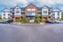 Contemporary apartment complex with brick facade, surrounded by lush landscaping and ample parking space.