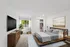 Modern bedroom with cozy bed, stylish wooden furniture, and large window overlooking greenery.