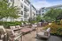 Charming apartment courtyard featuring lush greenery, comfortable seating, and vibrant flowers, perfect for relaxation and social gatherings.