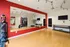 Contemporary home gym with vibrant red accent wall, spacious mirrored area, and fitness equipment for a perfect workout ambiance.
