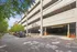 Spacious multi-level parking garage with modern design, surrounded by lush greenery and ample street parking.