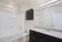 Modern bathroom featuring a sleek white bathtub, polished granite countertop with sink, and elegant dark cabinetry.