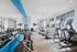 Bright and modern gym with state-of-the-art equipment, treadmills, dumbbells, and a large mirror wall for fitness enthusiasts.