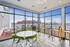 Bright and airy apartment lounge with modern design, vibrant seating area, and expansive city view from floor-to-ceiling windows.