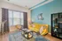 Chic living room featuring a vibrant yellow sofa, stylish wire chairs, and modern decor against a soothing teal accent wall.