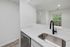 Sleek modern kitchen featuring a stylish black faucet, elegant marble countertops, and a view of lush greenery through the window.