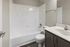 Modern bathroom featuring a sleek white bathtub, elegant vanity with polished faucet, and classic tile detailing.