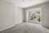 Bright, airy room with plush carpet and large window showcasing lush green views.