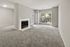Bright living room with plush carpet, large window views, and cozy fireplace in a modern apartment.