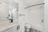 Elegant bathroom featuring modern fixtures, sleek white vanity, and glossy tiles, offering a luxurious retreat.