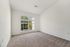 Bright, spacious bedroom with plush carpeting and large window offering garden views.