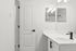 Modern bathroom with sleek white countertop, stylish black fixtures, and bright lighting.