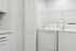 Modern laundry room with sleek white washer and dryer, complemented by a stylish countertop and ample shelving space.