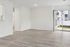 Bright, empty room featuring sleek wood flooring, sliding glass doors to a balcony, and abundant natural light creating a modern, spacious feel.