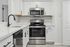Modern kitchen with sleek stainless steel appliances, elegant white cabinets, and marble countertops accented by chic subway tile backsplash.