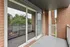Inviting brick balcony with glass sliding doors, offering a serene view of lush greenery and modern charm.