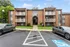 Attractive brick apartment building with spacious balconies and landscaped greenery, offering modern living in a serene environment.