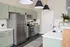 Elegant kitchen featuring mint green cabinets, stainless steel appliances, and sleek white countertops with modern fixtures.